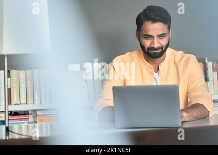 Indian business man using laptop in office thinking on online market analysis. Stock Photo