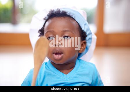 Ok spoon, are you ready to make some memories in the kitchen. an adorable baby boy wearing a chefs hat and holding a wooden spoon. Stock Photo