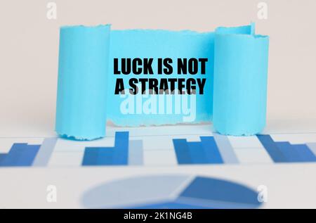 Business concept. On the blue diagram and graphs there is a twisted paper plate with the inscription - Luck is Not a Strategy Stock Photo