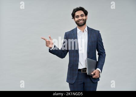 Smiling young indian arab business man wearing suit pointing isolated, portrait. Stock Photo