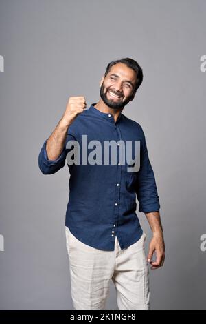 Happy indian business man celebrating good results isolated on gray background. Stock Photo