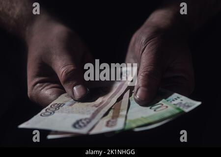 Man hands holding rubles money on a black background, close-up. Russian cash in the dirty hands of a poor man on a dark background Stock Photo