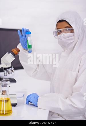 This is what Im testing today. A portrait of a young scientist in protective clothing holding up a test tube. Stock Photo