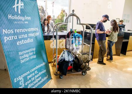 Bogota Colombia,Holiday Inn Bogota Airport inside interior lobby hotel front desk clerk guest luggage cart sign bilingual Spanish English renovation c Stock Photo