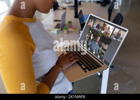 Midsection of african american businesswoman discussing with colleagues on videocall over laptop Stock Photo