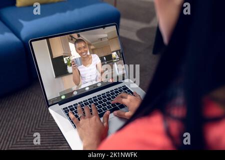 Multiracial female coworkers talking on video conference over laptop at home Stock Photo