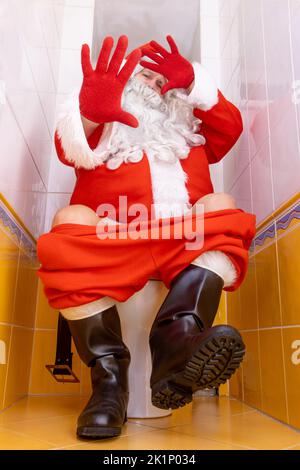 Santa Claus is surprised from the paparazzi photographer when sitting on the toilet Stock Photo