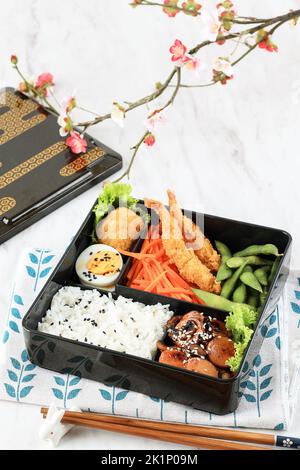 Japanese Bento Set with Shrimp Tempura, Boiled Egg, Nugget, Teriyaki Sausage, Carrot, and Edamame Stock Photo