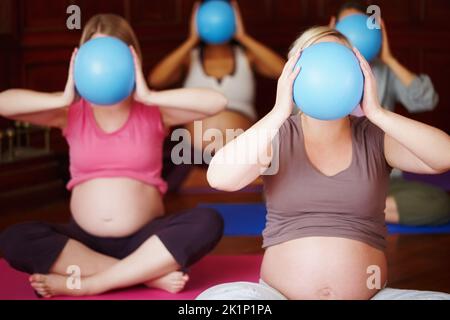 Facing their fitness needs. A group of pregnant women exercising their arms in a yoga class using exercise balls. Stock Photo