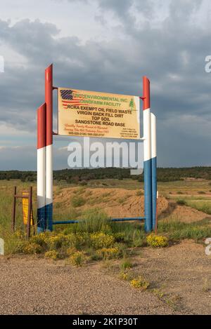 A sign for TNTEnvironmental Inc Landfill Facility, RCRA Exempt Oil Field Waste with red, white and blue fence posts, Northern New Mexico. Stock Photo