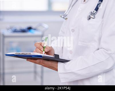 Taking notes help discover symptoms. an unrecognizable doctor making notes on a clipboard. Stock Photo