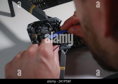 close up of mans hands repairing a drone on white table with different tools Stock Photo