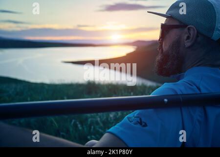 Portrait of bearded Man in silhouette holding SUP board paddle near lake at sunset in Kazakhstan. Stand up paddle boarding outdoor active recreation i Stock Photo