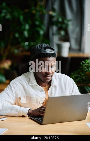 Young African American businessman concentrating on work with online data while sitting in front of laptop and preparing presentation Stock Photo