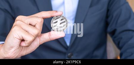 Businessman hand holding Silver Litecoin (LTC) cryptocurrency, Crypto is Digital Money within the blockchain network, is exchanged using technology an Stock Photo