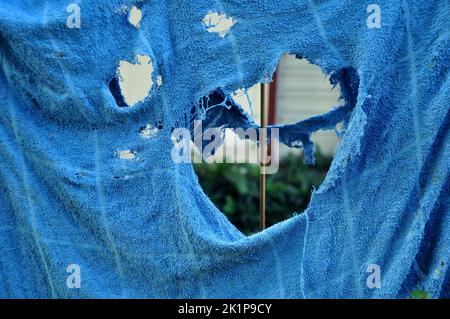 Torn blue towel hanging on a fence Stock Photo