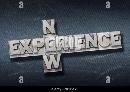 new experience crossed phrase made from metallic letterpress on dark jeans background Stock Photo