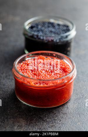Red and black caviar in jar on the dark table. Stock Photo