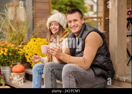 Cheerful young couple seated on the veranda Stock Photo