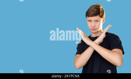 No gesture. Teen protest. Restriction refusal. Disagreement opposition. Portrait of disappointed guy in black t-shirt showing X sign with crossed hand Stock Photo
