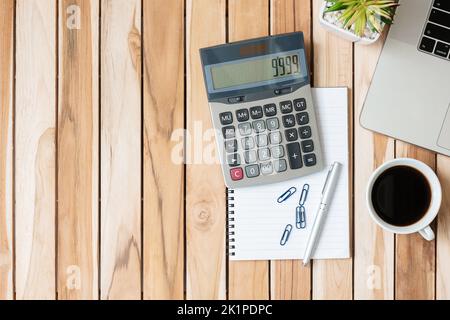 Top view Office desk with calculator, pen, blank notebook, paperclip, computer laptop and coffee cup  on wood table background. workspace or home offi Stock Photo
