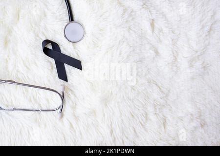 black Ribbon and stethoscope on white background. Melanoma and skin cancer, Vaccine injury awareness month and rest in peace concepts Stock Photo