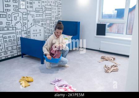 Female picking up children clothing off the carpet Stock Photo