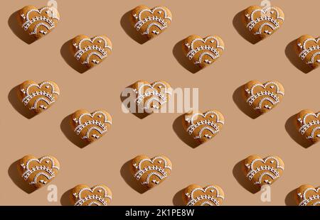 Lovely bakery seamless pattern. Festive pastry design. Holiday gift celebration. Decorated white ornament icing gingerbread hearts isolated on beige p Stock Photo