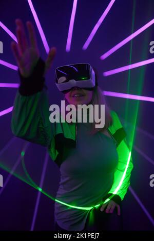 Woman is using virtual reality headset to access in metaverse. Concept of virtual, augmented and extended reality, future technology, artificial intel Stock Photo