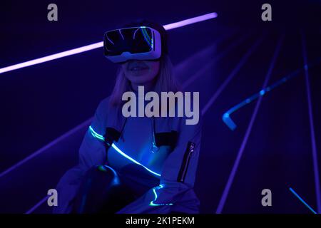 Woman is using virtual reality headset to access in metaverse. Concept of virtual, augmented and extended reality, future technology, artificial intel Stock Photo