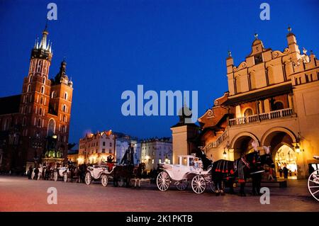 Krakow carriages in front of Old Town near Cloth Hall and Basilica of the Virgin Mary in Poland. Stock Photo