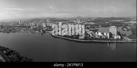 A black and white aerial panoramic of a city with a beautiful landscape in the background Stock Photo