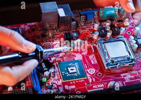 A man soldering a motherboard. Repair and maintenance of desktop personal computers and laptops. Stock Photo