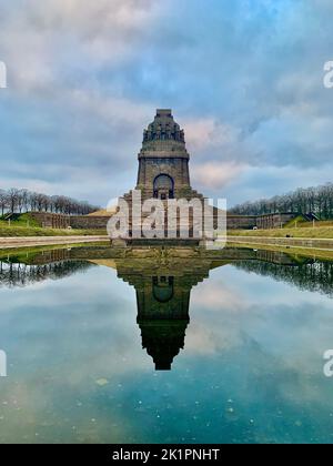 A vertical shot of the Monument to the Battle of the Nations monument in Leipzig against a cloudy sky Stock Photo