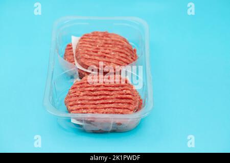 fresh raw minced meat in plastic box on blue paper Stock Photo