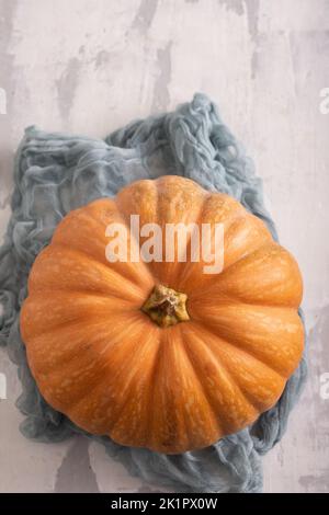 Fresh orange pumpkin with napkin on grey ceramic. Top view. Stock Photo