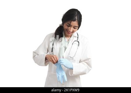 Young Venezuelan female doctor smiling and wearing blue gloves, isolated. Stock Photo