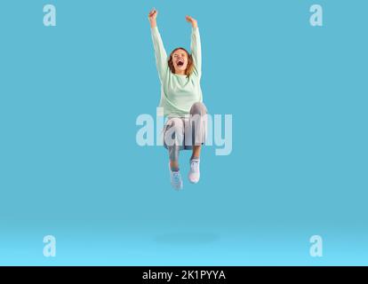 Joyful excited woman clenching her fists rejoicing in her victory or success jumping in air. Stock Photo