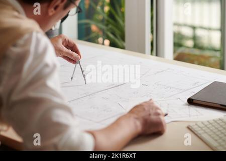 Civil engineer drawing with compass when working on building plan Stock Photo