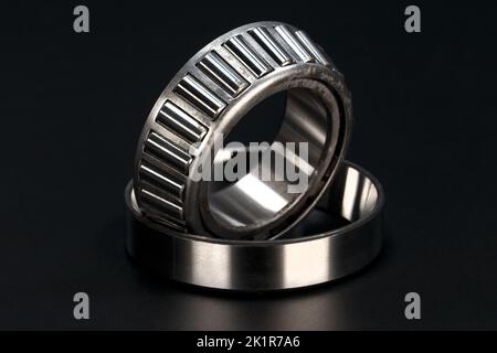 Roller bearing with cage on black background. Close-up. Stock Photo