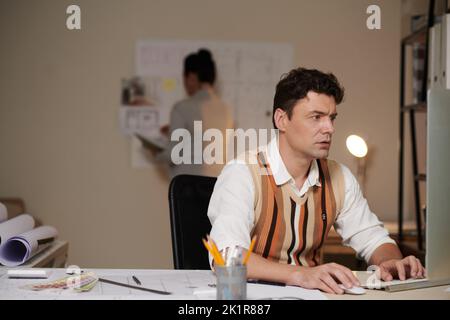 Serious architect working on computer at his desk in architectural bureau Stock Photo