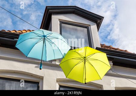 Colorful umbrellas in the air against blue sky with clouds Stock Photo