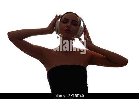 Woman silhouette. Music chillout. Sound relaxation. Dark contrast shape portrait of peaceful lady enjoying listening to audio in wireless headphones i Stock Photo