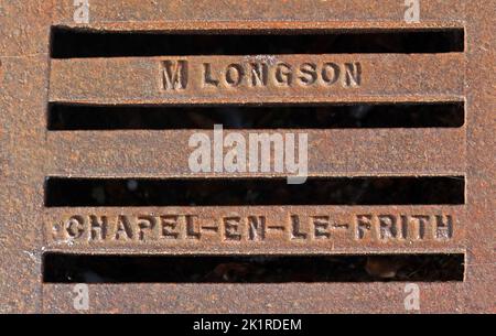 Embossed rusty cast iron grid, Chapel-en-le-frith and M Longson, High Peak, Derbyshire, England, UK, SK23 0BA Stock Photo