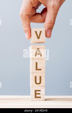 Business man hand holding wooden cube block with Value business word on table background. Mission, Vision and core values concept Stock Photo