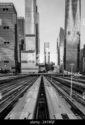 A vertical grayscale shot of midtown New York with subway transports under tall skyscrapers Stock Photo