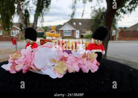Kesgrave, Ipswich, Suffolk - 20 September 2022 : Crochet post box topper for Queen Elizabeth II. Guardsman, coffin, crown and flower details on a black cover. Stock Photo