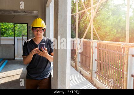 Engineer or Architect using cell phone in building construction site. Stock Photo