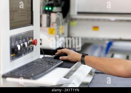 Operator controls a modern woodworking CNC machine. Selective focus. Stock Photo