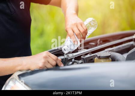 male hand pouring water filling car radiator with concentrated coolant or distilled water for cool engine in summer season Stock Photo